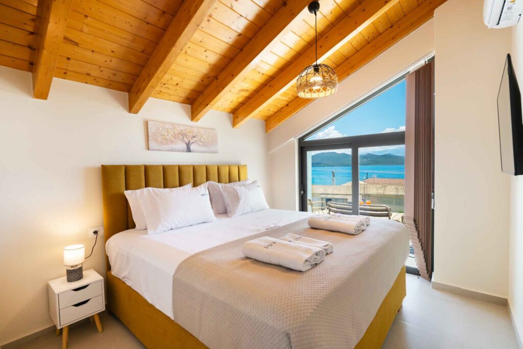 Bright master bedroom at Poseidon Maisonette in Nikiana, Lefkada, featuring a comfortable double bed, modern furnishings, and a relaxing atmosphere.