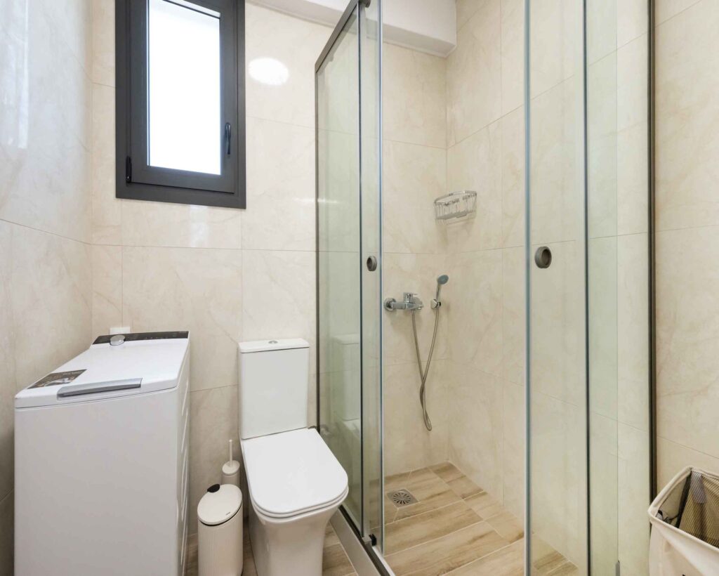 Modern bathroom at Poseidon Maisonette in Nikiana, Lefkada, featuring a walk-in shower, contemporary design, and essential amenities.
